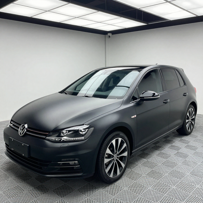 Full car wrap vinyl film transformation matte black wrap on white hatchback in professional auto studio